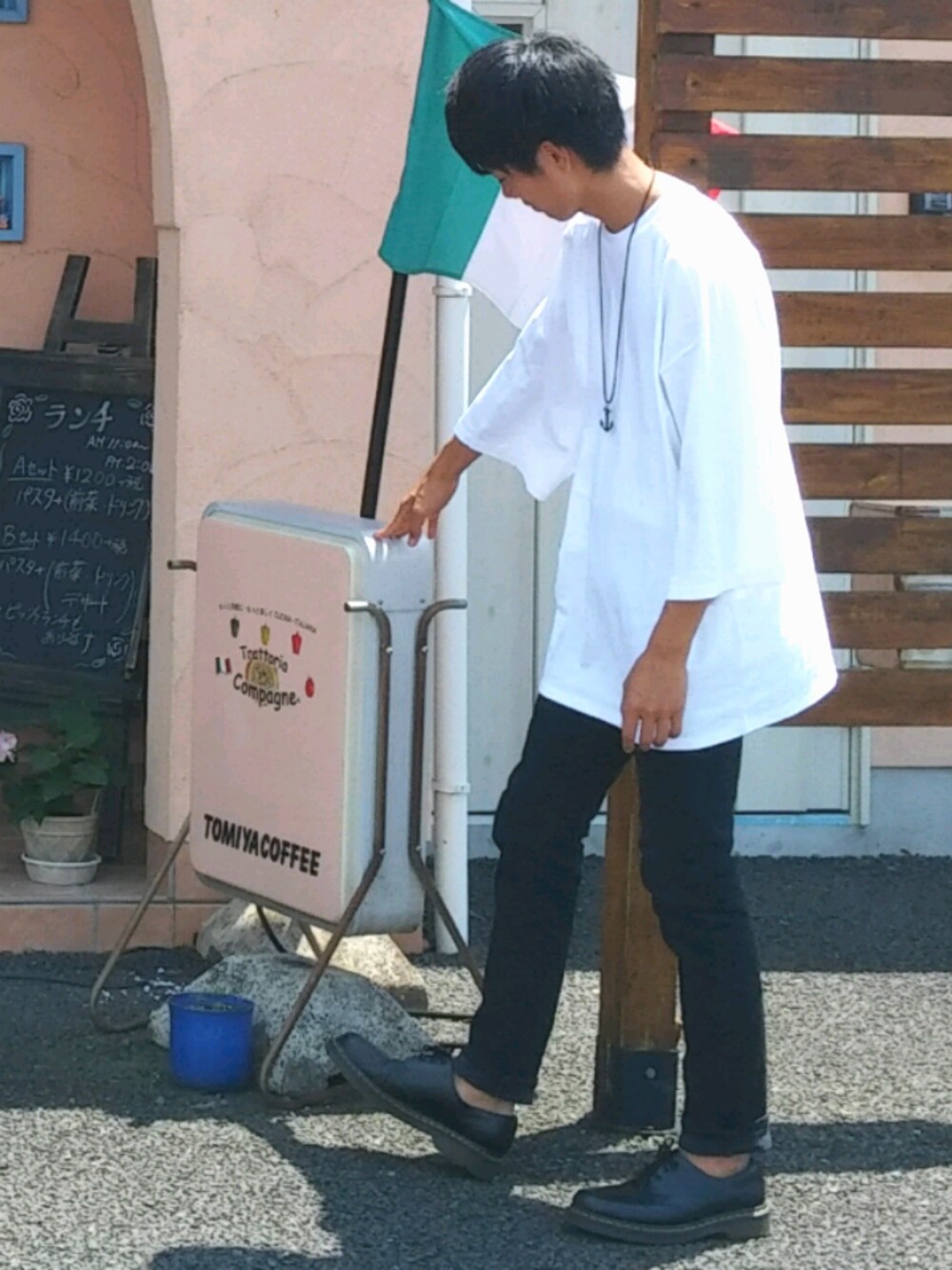 ブラック系のデニムパンツ、ブラック系のドレスシューズ、ホワイト系のTシャツ/カットソーを着用したメンズの夏コーディネートの1枚目の写真