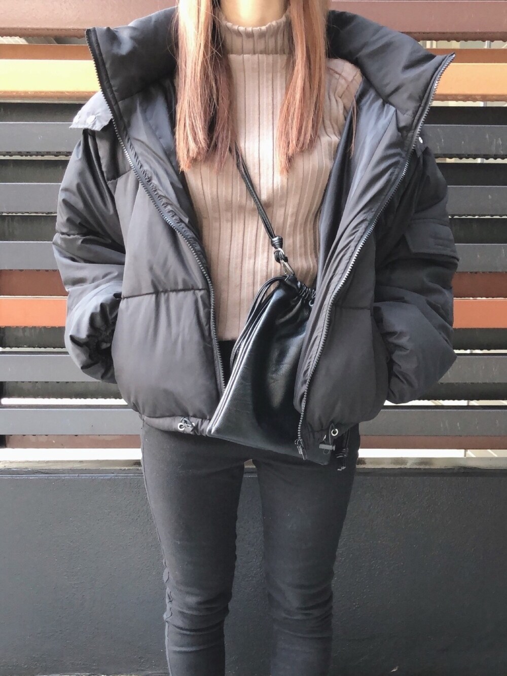 ブラック系のダウンジャケット/コート、ブラウン系のニット/セーター、ブラック系のショルダーバッグを着用したレディースの冬コーディネートの1枚目の写真