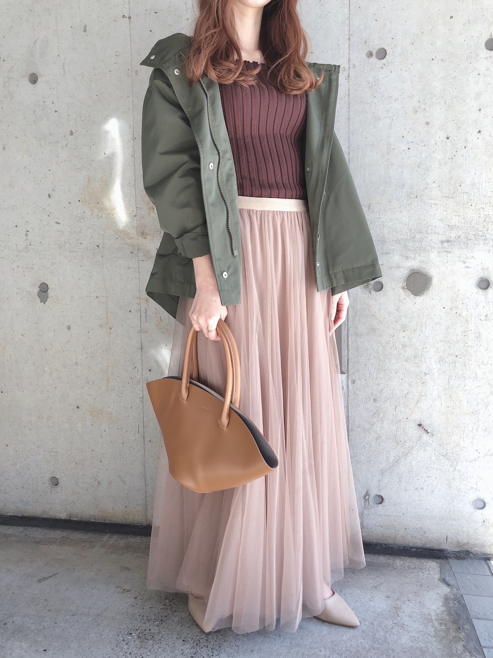 イエロー系のハンドバッグ、ベージュ系のスカート、ブラウン系のニット/セーターを着用したレディースの春コーディネートの1枚目の写真