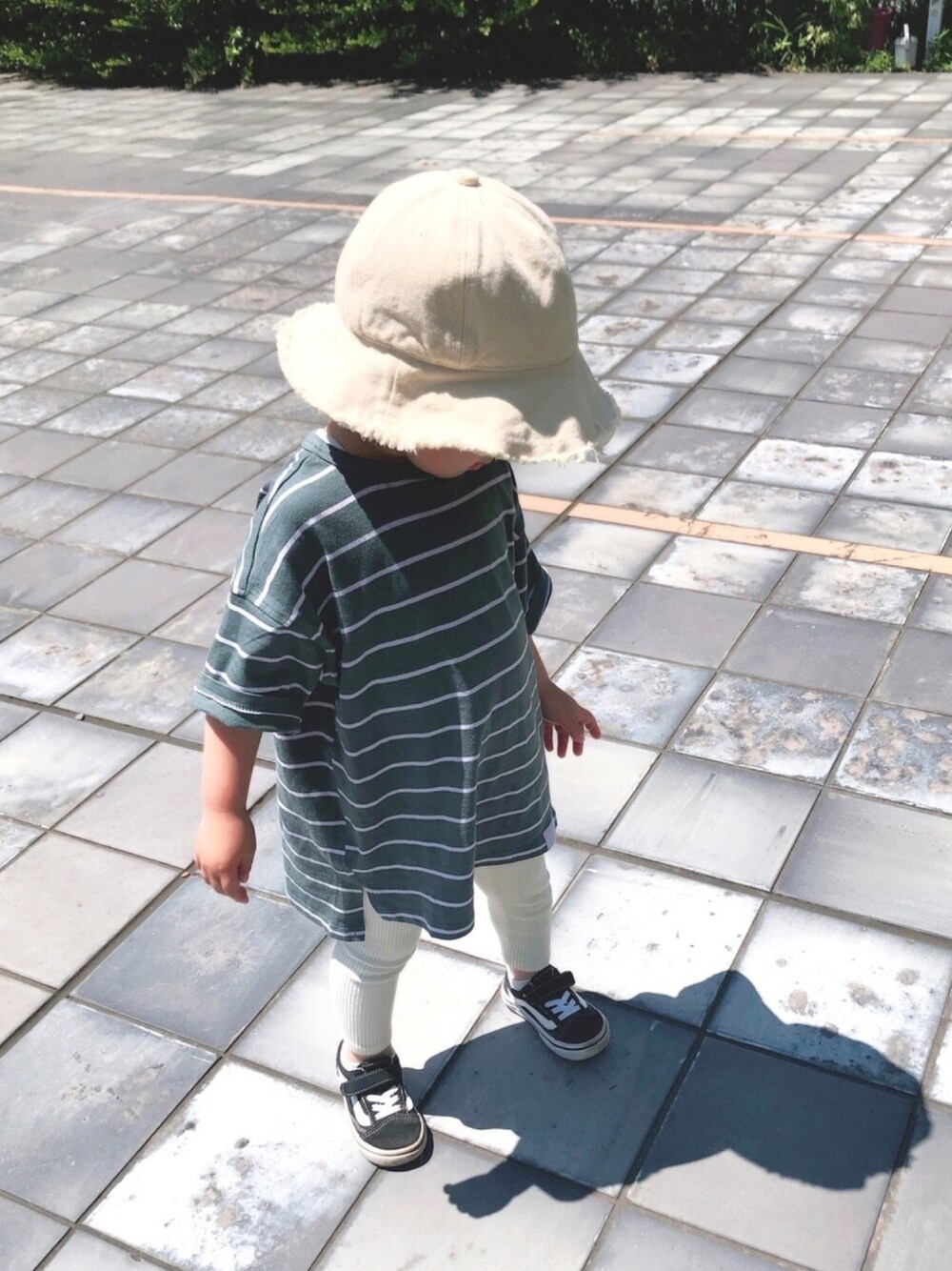 グリーン系のTシャツ/カットソー、ブラック系のスニーカー、ホワイト系のハットを着用したキッズの春コーディネートの1枚目の写真