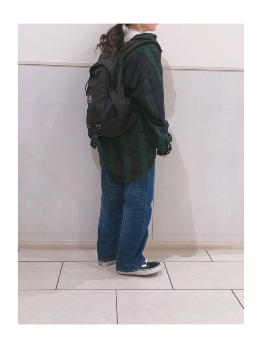 ブラック系のバックパック/リュック、ブルー系のデニムパンツ、グリーン系のシャツ/ブラウスを着用したレディースの冬コーディネートの1枚目の写真