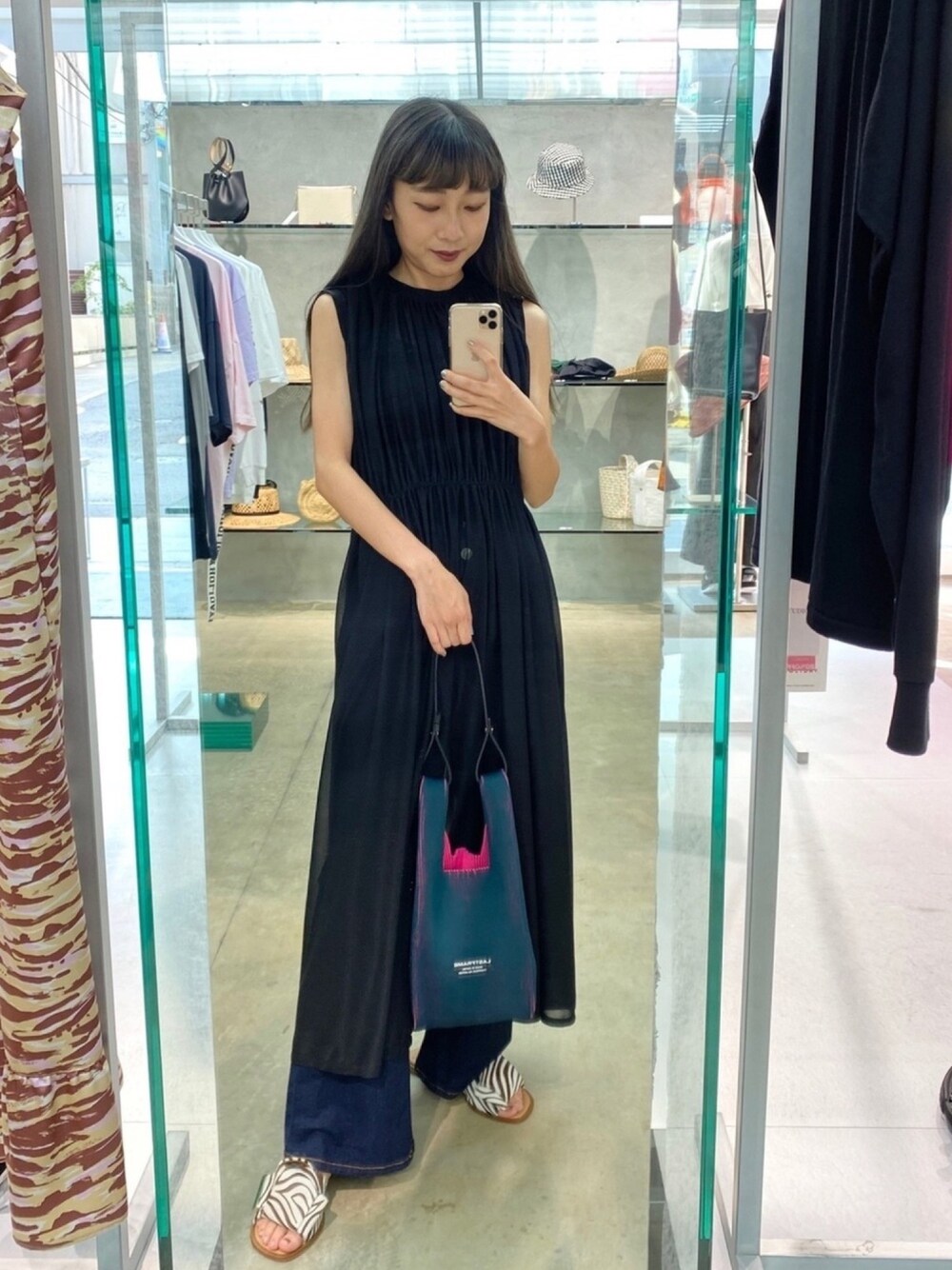 グリーン系のショルダーバッグ、ブルー系のデニムパンツ、ブラウン系のサンダルを着用したレディースの夏コーディネートの1枚目の写真