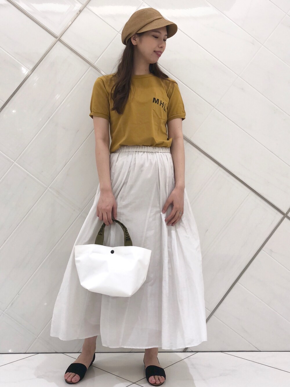 イエロー系のTシャツ/カットソー、グレー系のスカート、ホワイト系のトートバッグを着用したレディースの春コーディネートの1枚目の写真