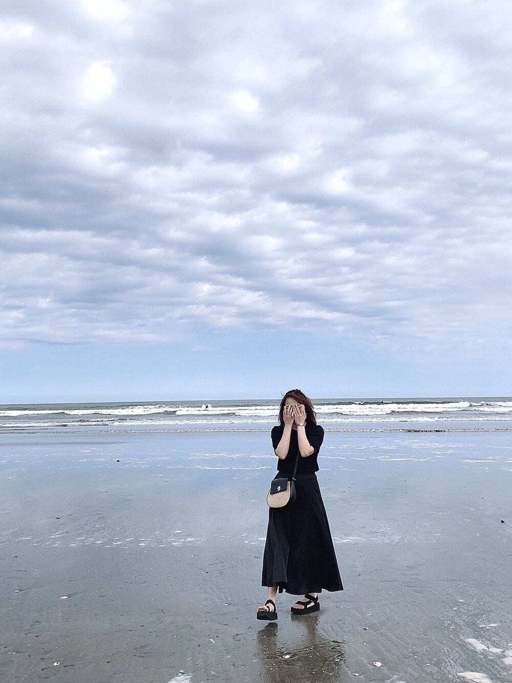 ブラック系のスカート、ブラック系のサンダル、ブラック系のバッグを着用したレディースの春コーディネートの1枚目の写真