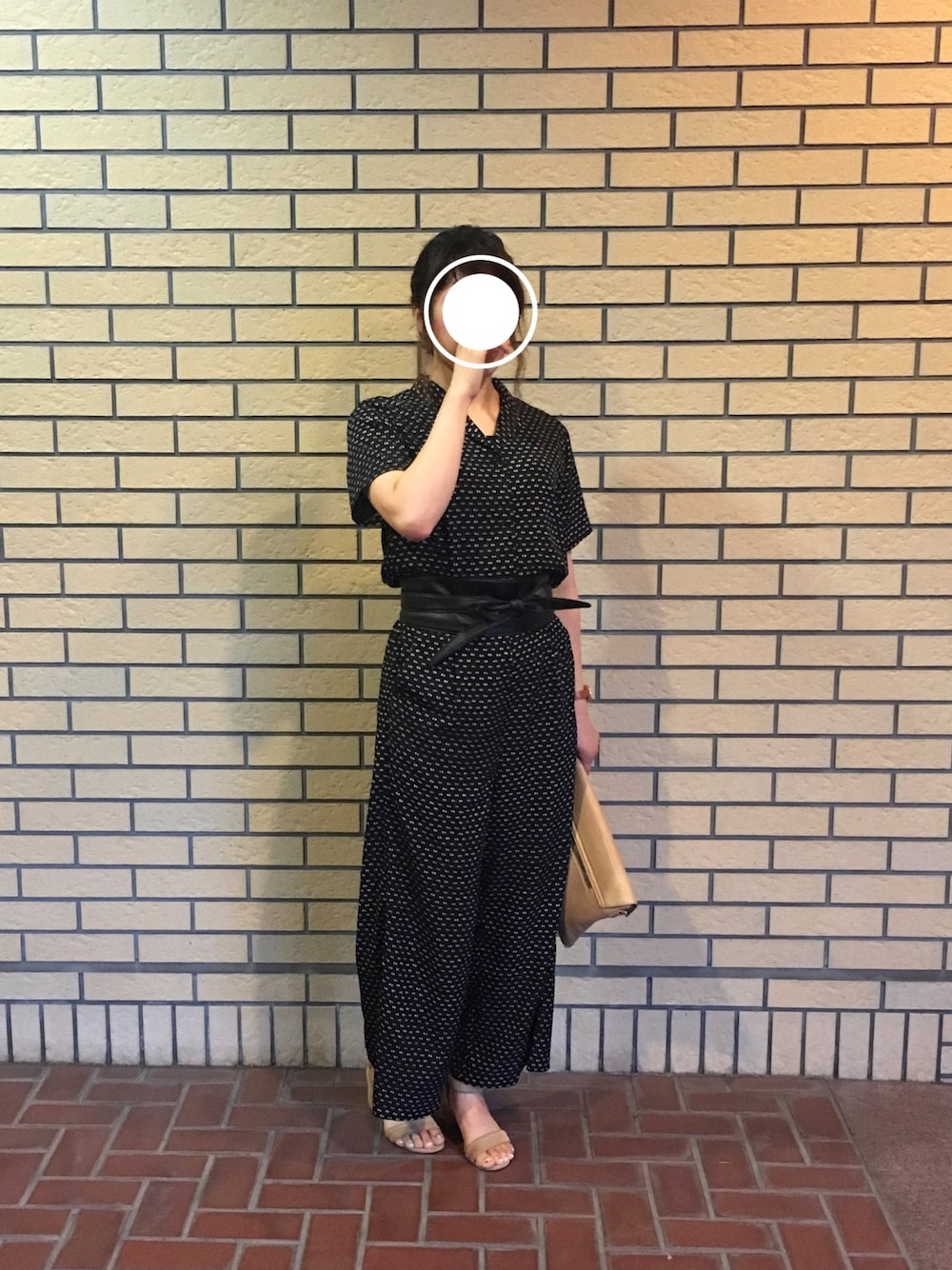 ブラック系のワンピース、ベージュ系のクラッチバッグ、ベージュ系のサンダルを着用したレディースの夏コーディネートの1枚目の写真