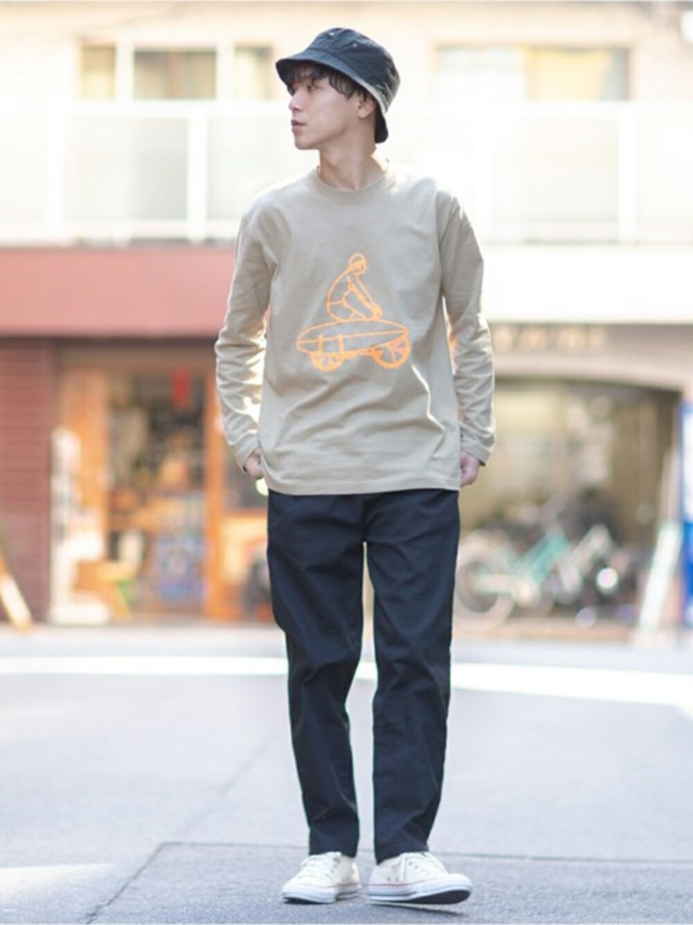 グリーン系のTシャツ/カットソー、ブラック系のチノパンツを着用したメンズの春コーディネートの1枚目の写真