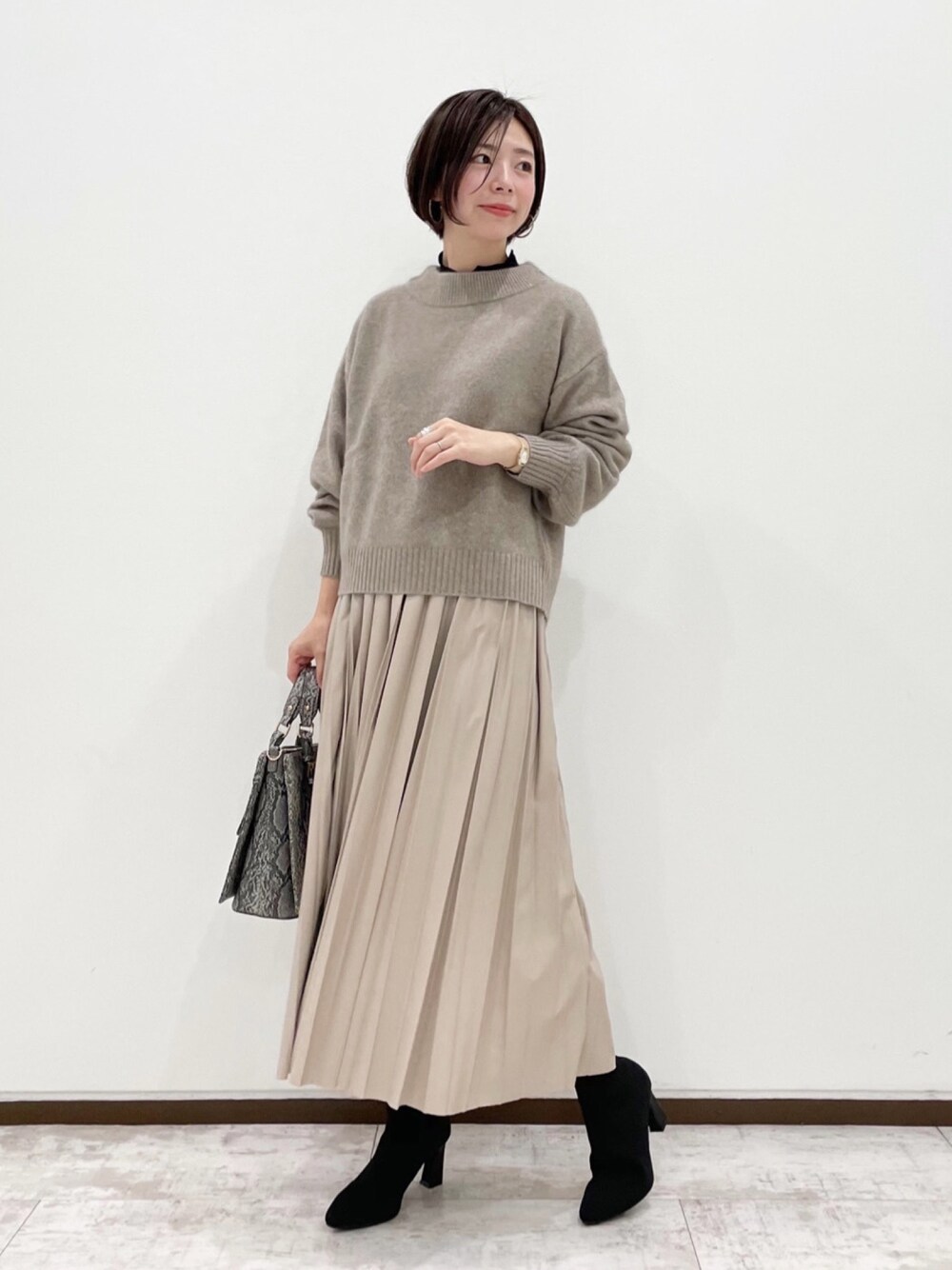 ブラウン系のニット/セーター、ブラック系のTシャツ/カットソー、ベージュ系のスカートを着用したレディースの冬コーディネートの1枚目の写真