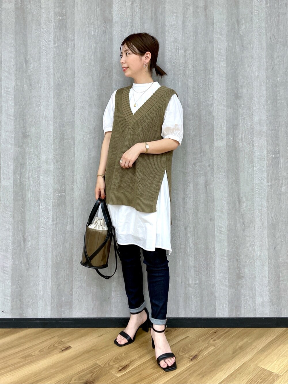 グリーン系のトップス、ブルー系のデニムパンツ、ブラック系のショルダーバッグを着用したレディースの春コーディネートの1枚目の写真