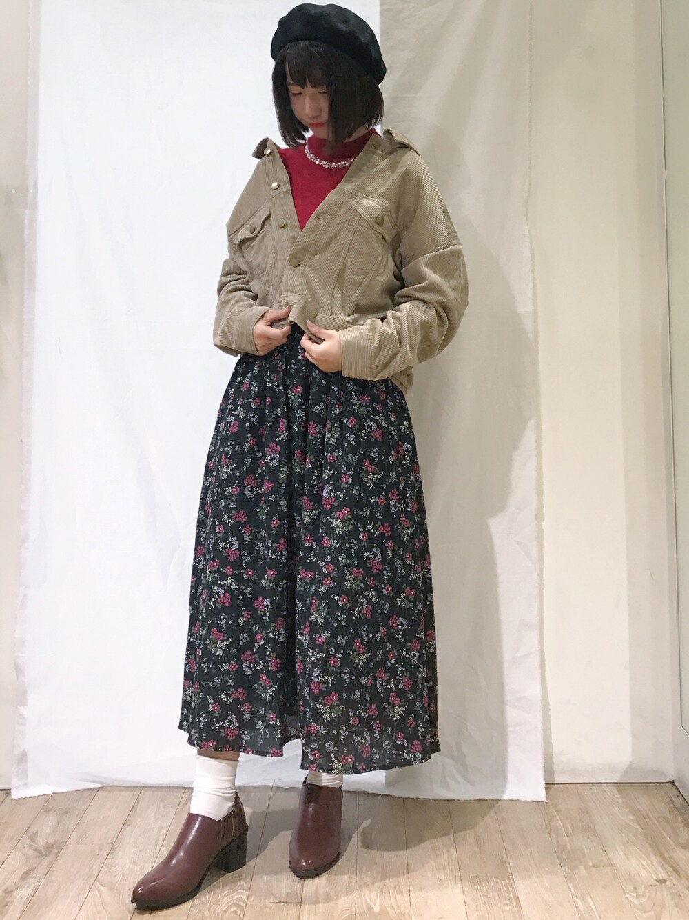 レッド系のニット/セーター、ベージュ系のその他アウター、ブラック系のスカートを着用したレディースの秋コーディネートの1枚目の写真
