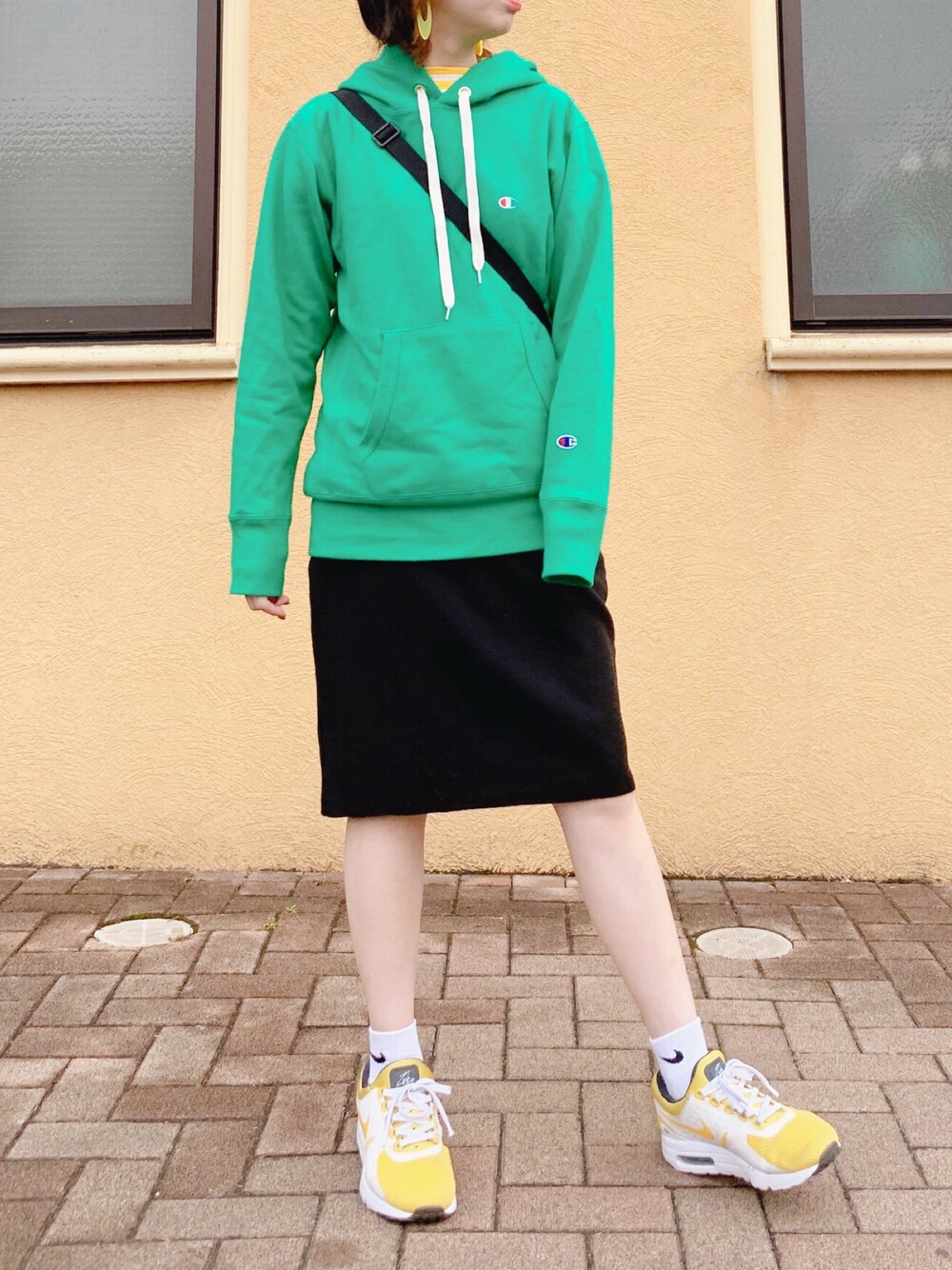 グリーン系のパーカー、イエロー系のTシャツ/カットソー、ブラック系のショルダーバッグを着用したレディースの春コーディネートの1枚目の写真