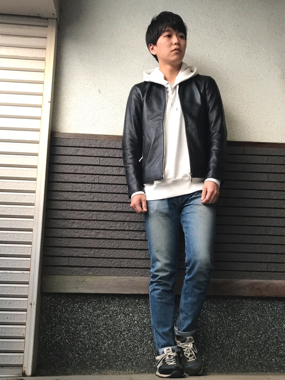 ブラック系のライダースジャケット、ホワイト系のパーカー、ブルー系のデニムパンツを着用したメンズの秋コーディネートの1枚目の写真
