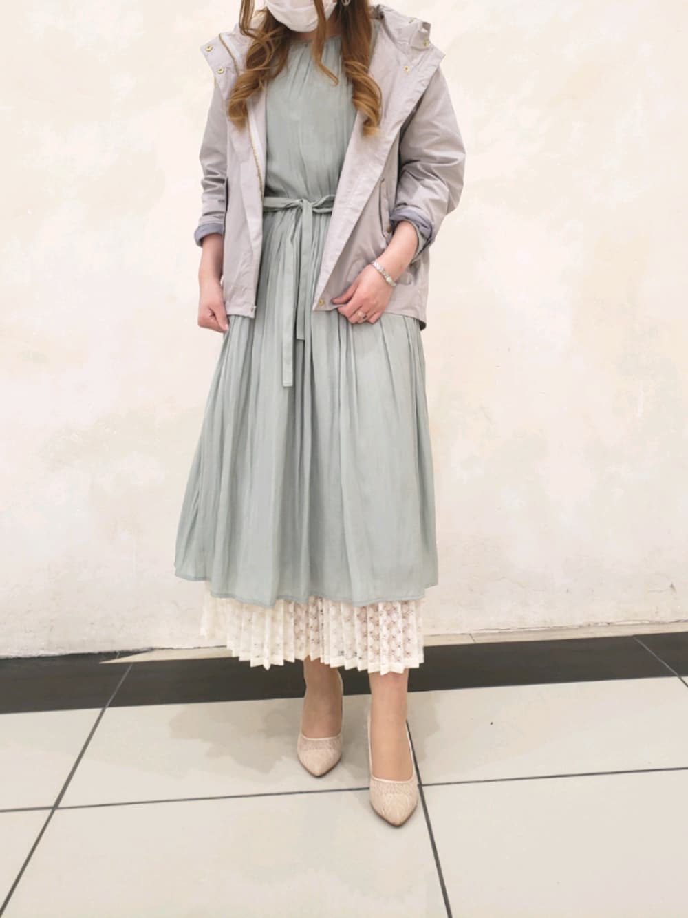 ホワイト系のスカート、グリーン系のワンピース、ベージュ系のマウンテンパーカーを着用したレディースの冬コーディネートの1枚目の写真