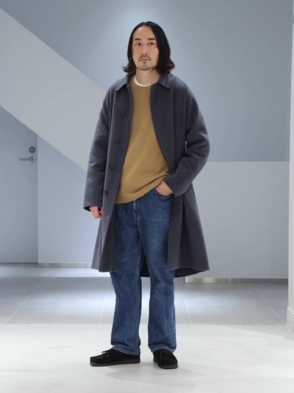 ホワイト系のTシャツ/カットソー、ブラウン系のニット/セーター、ブルー系のステンカラーコートを着用したメンズの秋コーディネートの1枚目の写真