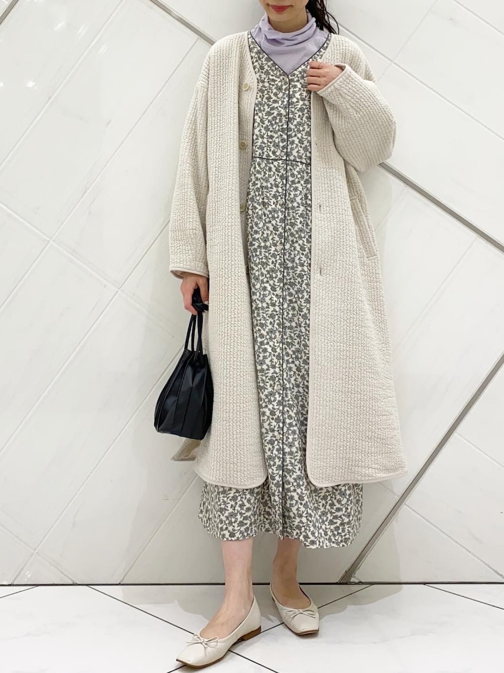 ホワイト系のワンピース、ホワイト系のノーカラーコート、ブラック系のハンドバッグを着用したレディースの冬コーディネートの1枚目の写真