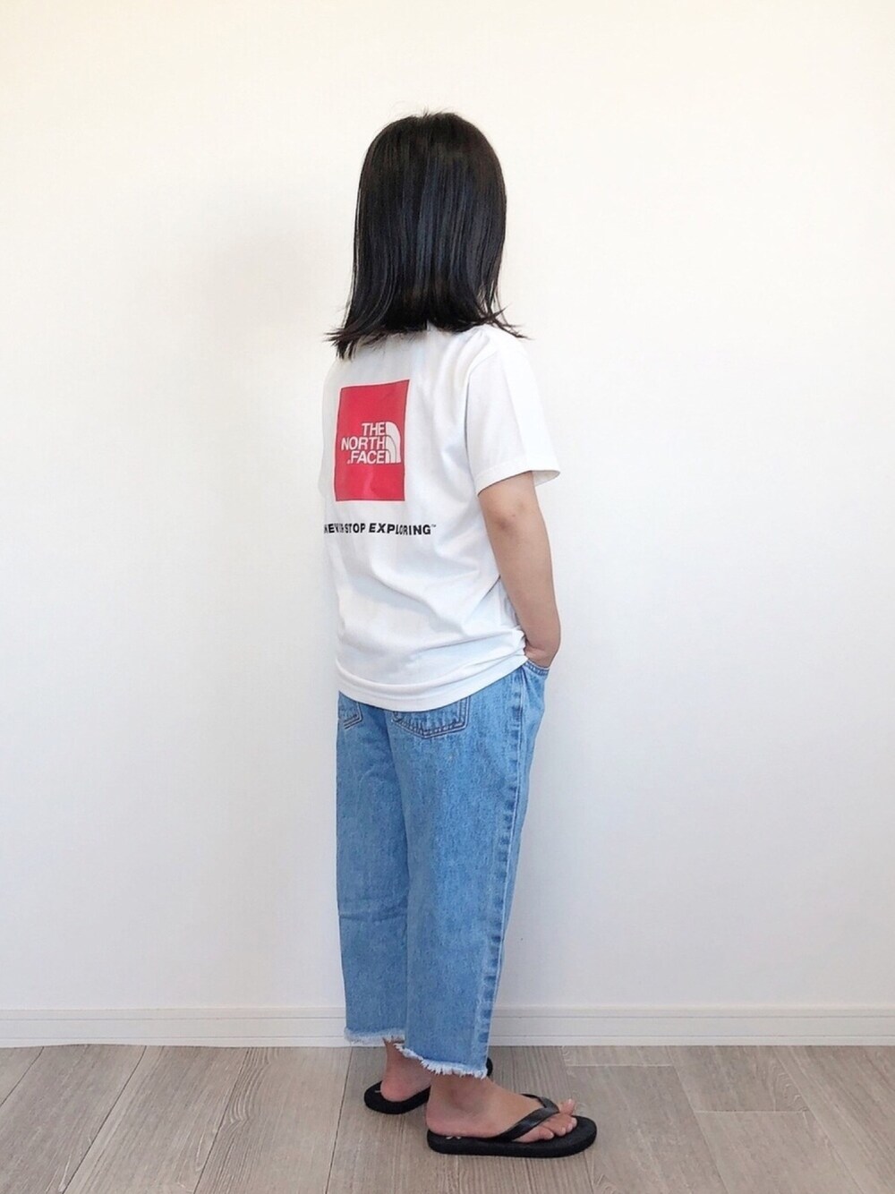 ホワイト系のTシャツ/カットソー、ブルー系のデニムパンツ、ブラック系のサンダルを着用したキッズの秋コーディネートの1枚目の写真