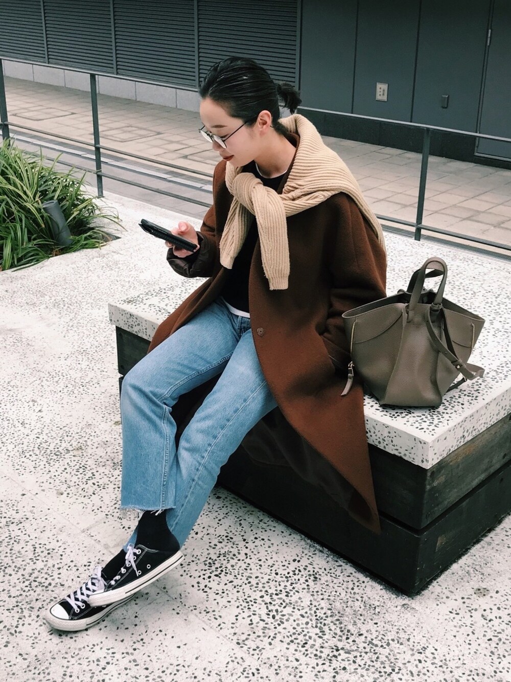 ブラウン系のノーカラージャケット、ブルー系のデニムパンツ、ブラック系のスニーカーを着用したレディースの冬コーディネートの1枚目の写真