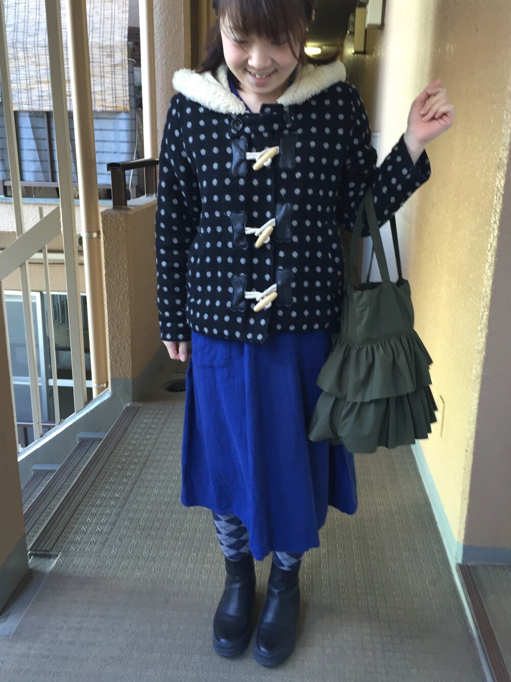 ブラック系のダッフルコート、ブルー系のワンピース、グリーン系のトートバッグを着用したレディースの冬コーディネートの1枚目の写真