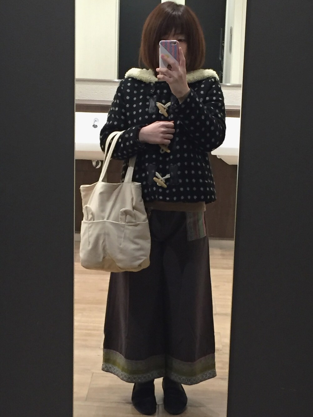 ベージュ系のトートバッグ、ブラック系のダッフルコート、ホワイト系のニット/セーターを着用したレディースの冬コーディネートの1枚目の写真