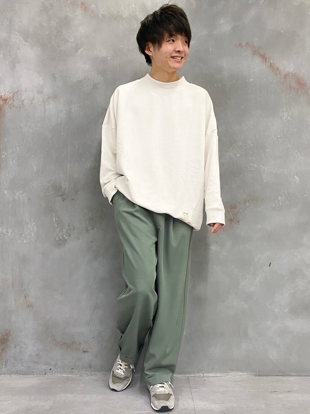 ホワイト系のスウェット、グリーン系のスラックス、グレー系のスニーカーを着用したメンズの冬コーディネートの1枚目の写真