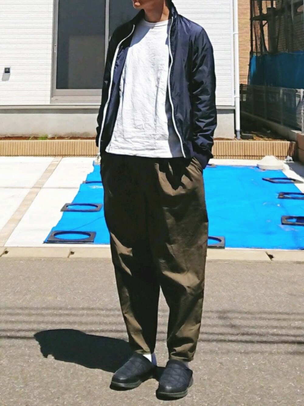 グリーン系のパンツ、ブラック系のスリッポン、ブルー系のトップスを着用したメンズの春コーディネートの1枚目の写真