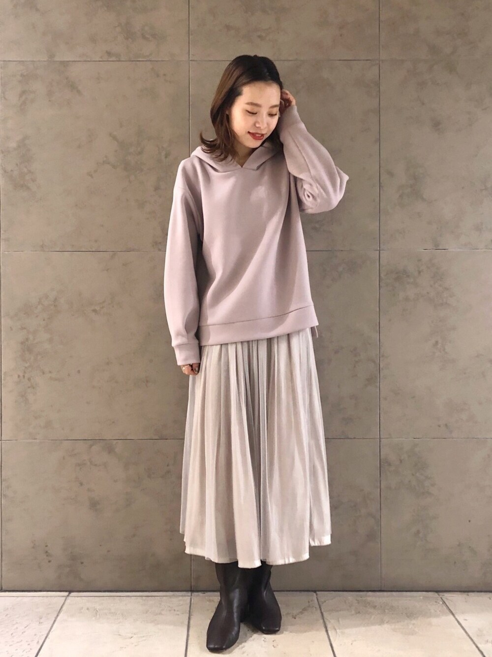 パープル系のパーカー、ベージュ系のスカート、ブラウン系のブーツを着用したレディースの冬コーディネートの1枚目の写真