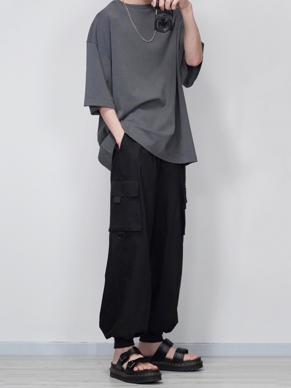 グレー系のTシャツ/カットソー、ブラック系のカーゴパンツ、ブラック系のサンダルを着用したメンズの春コーディネートの1枚目の写真