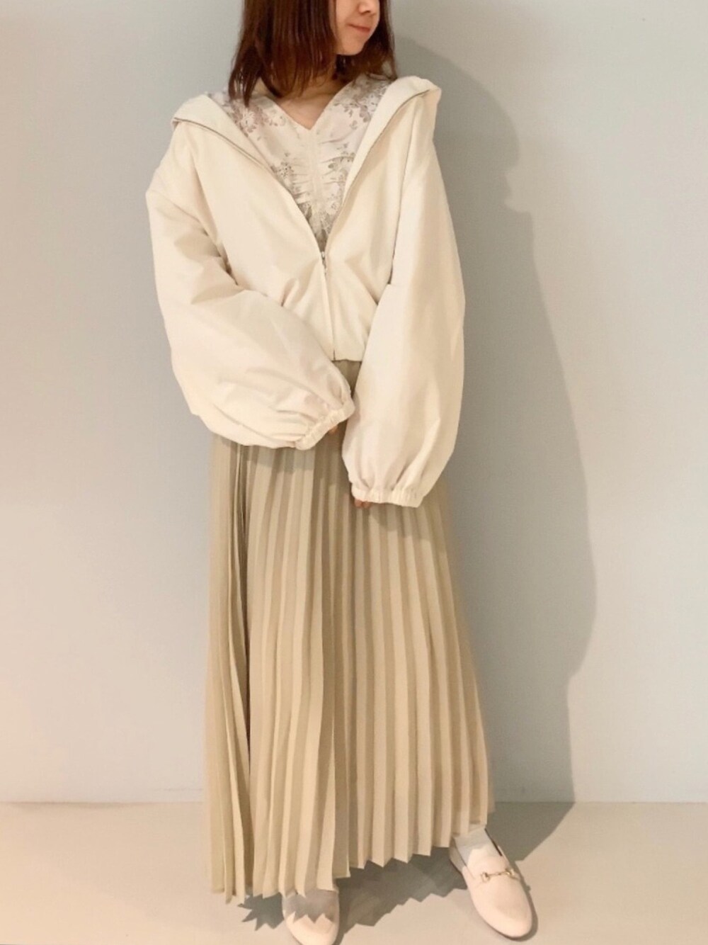 ベージュ系のスカート、ホワイト系のローファー、ホワイト系のブルゾンを着用したレディースの春コーディネートの1枚目の写真