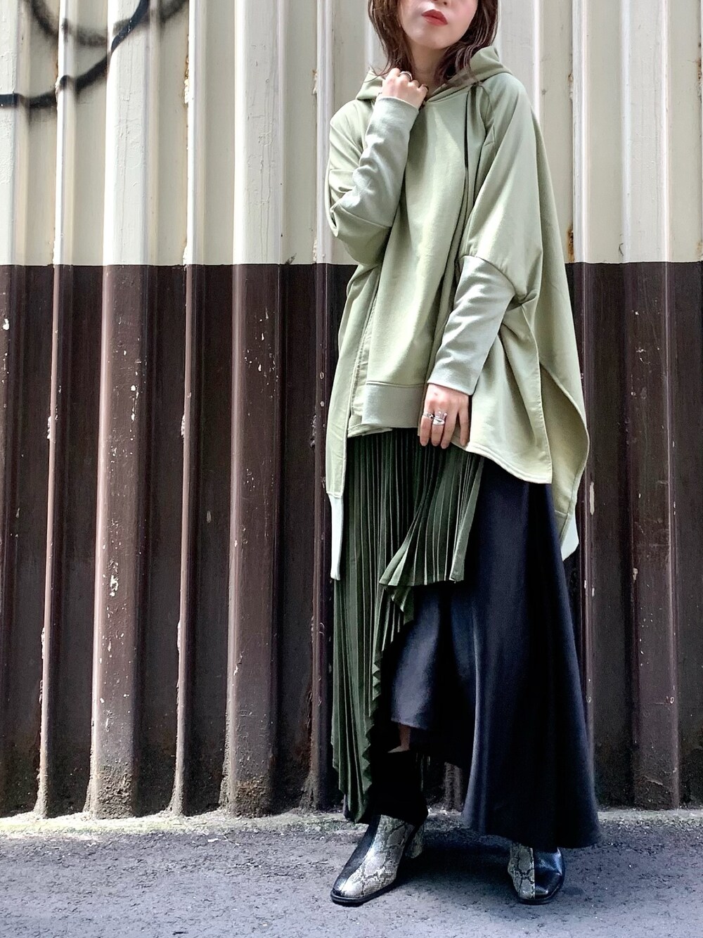 グリーン系のパーカー、グリーン系のスカートを着用したレディースの秋コーディネートの1枚目の写真
