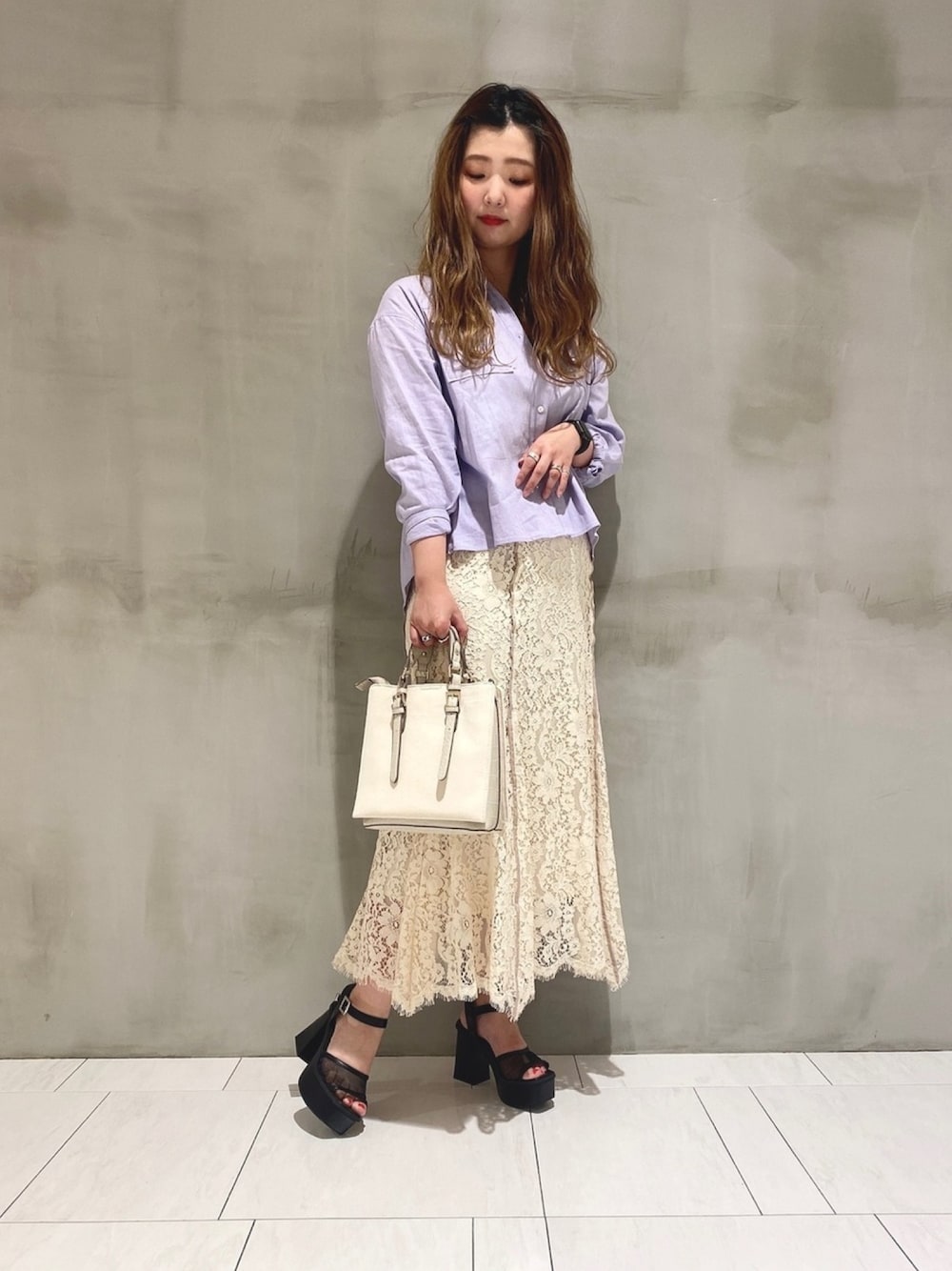 ホワイト系のスカート、ブラック系のサンダル、ベージュ系のバッグを着用したレディースの春コーディネートの1枚目の写真