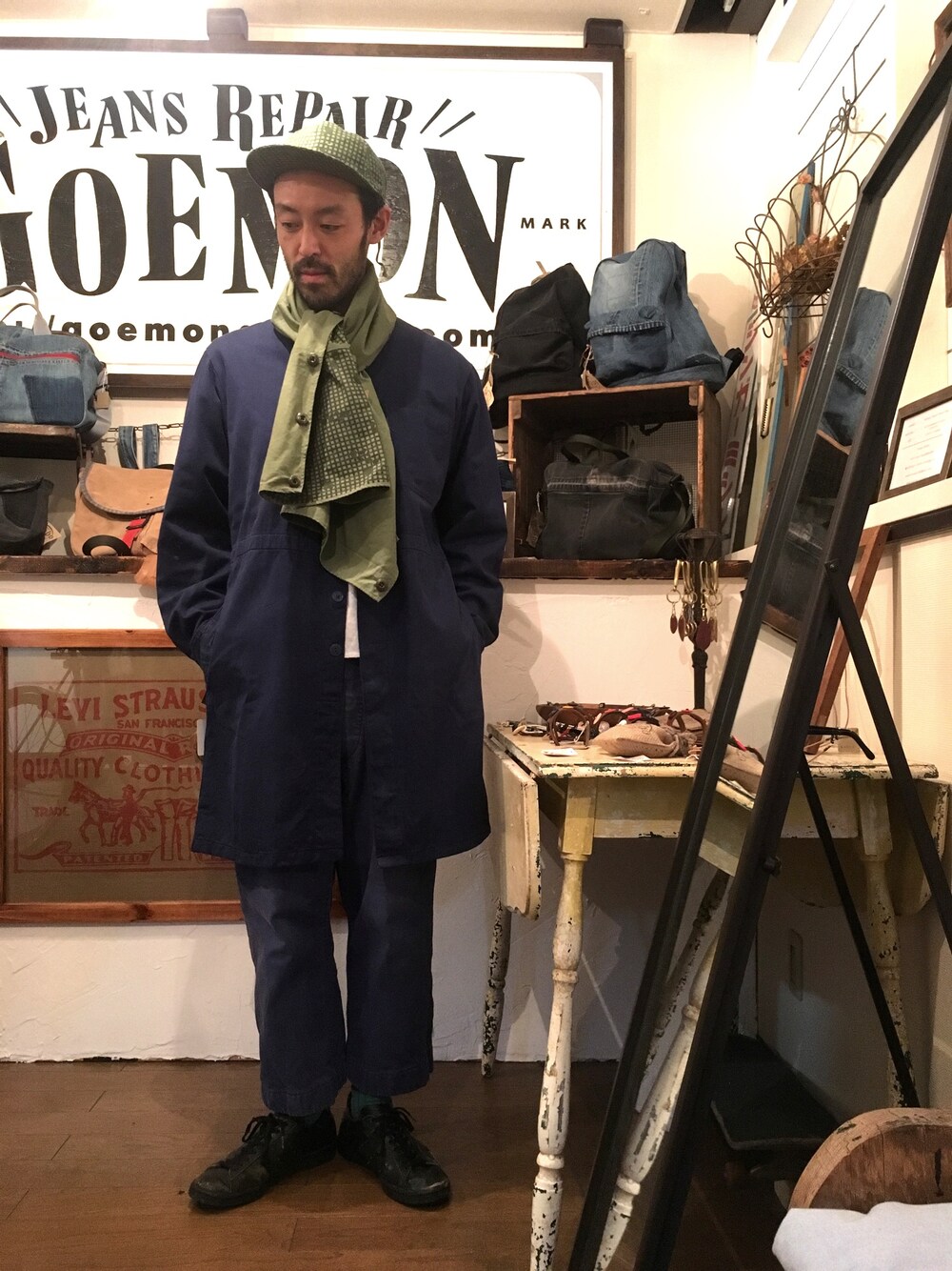 ブルー系のノーカラージャケット、その他のキャップ、グリーン系のストール/ショールを着用したメンズの春コーディネートの1枚目の写真