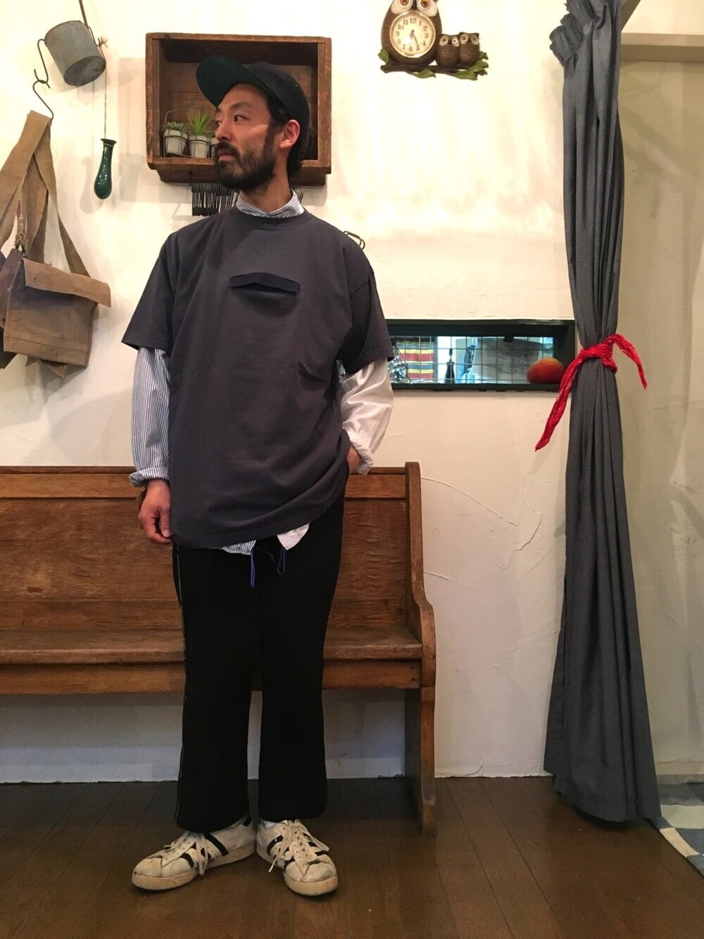 ブラック系のスラックス、グレー系のTシャツ/カットソー、ブルー系のキャップを着用したメンズの春コーディネートの1枚目の写真