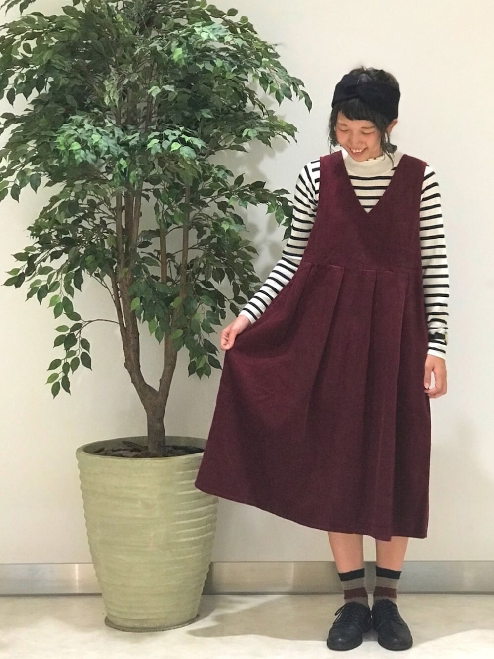 ホワイト系のニット/セーター、レッド系のジャンパースカート、ブラック系のヘアバンドを着用したレディースの秋コーディネートの1枚目の写真