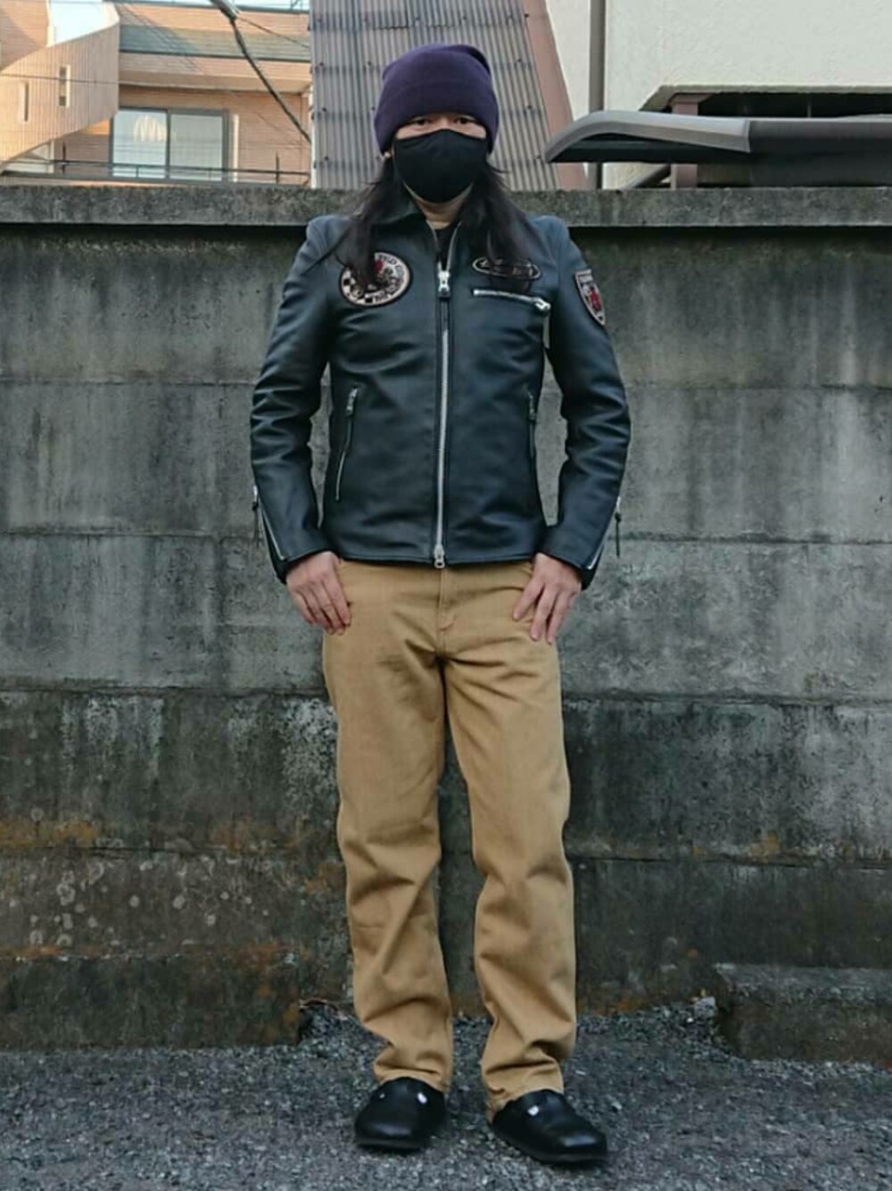 ブラック系のライダースジャケット、ブラウン系のパンツ、ブラック系のサンダルを着用したメンズの冬コーディネートの1枚目の写真