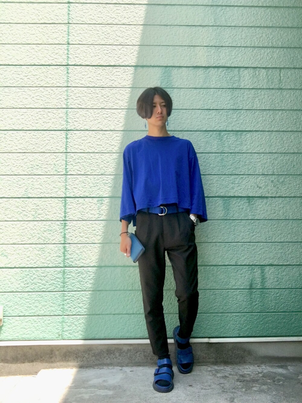 ブルー系のTシャツ/カットソー、ブラック系のスラックス、ブルー系のサンダルを着用したメンズの夏コーディネートの1枚目の写真