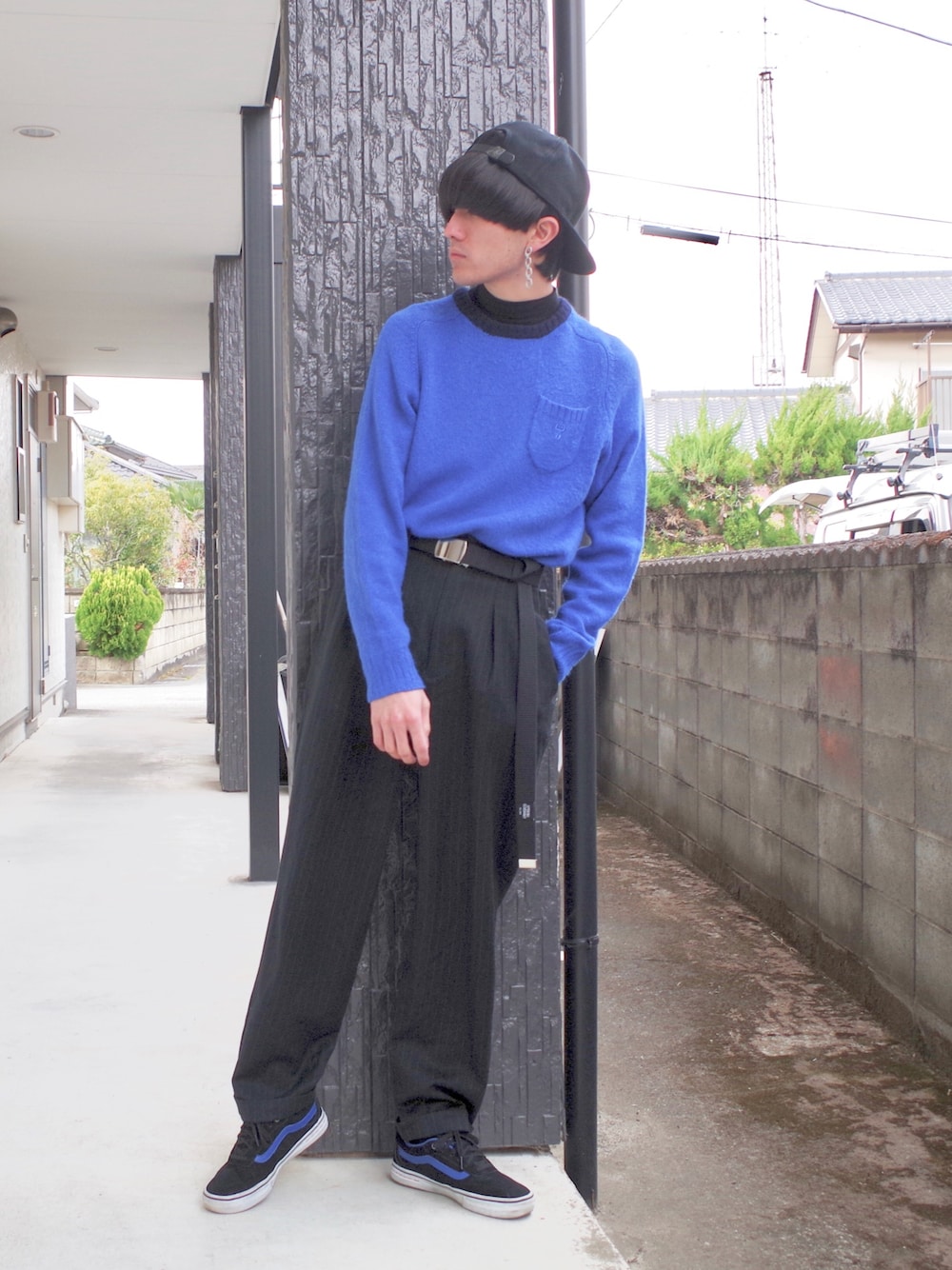 ブルー系のニット/セーター、ブラック系のスニーカー、ブラック系のスラックスを着用したメンズの春コーディネートの1枚目の写真