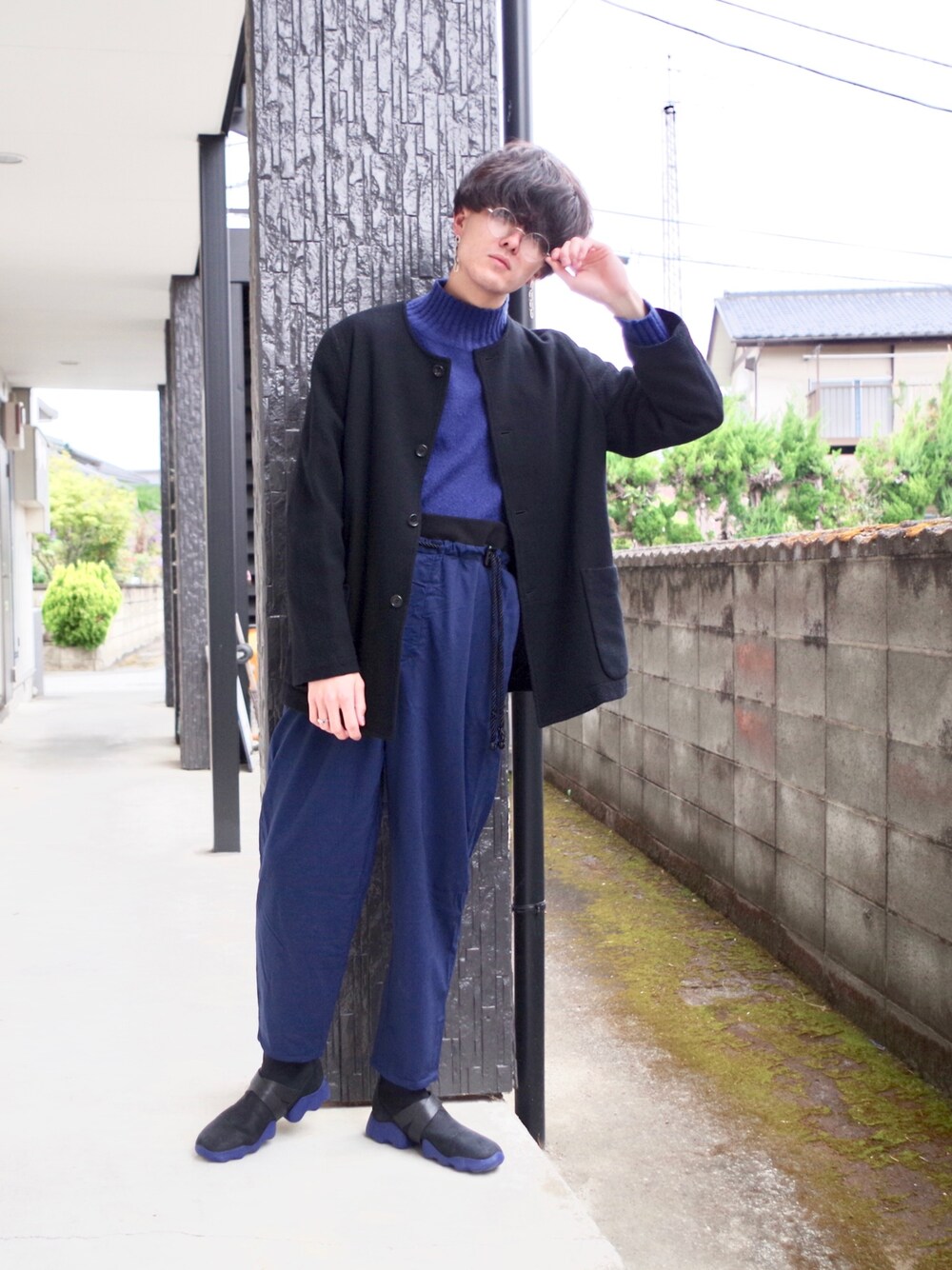 ブルー系のニット/セーター、ブラック系のノーカラージャケット、ブルー系のスラックスを着用したメンズの春コーディネートの1枚目の写真