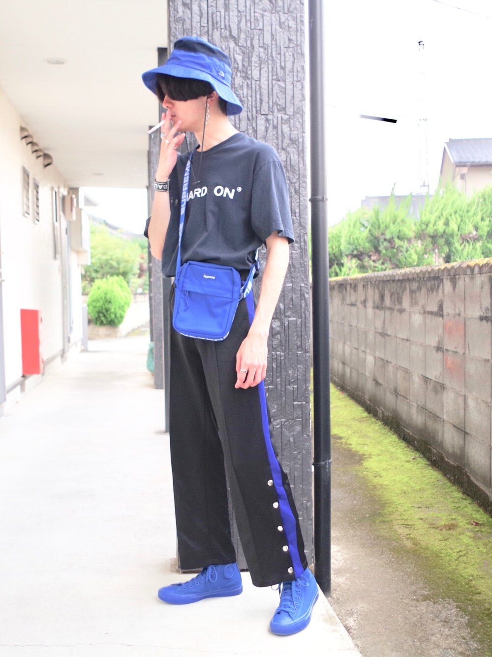 ブラック系のTシャツ/カットソー、ブルー系のショルダーバッグ、ブラック系のパンツを着用したメンズの秋コーディネートの1枚目の写真