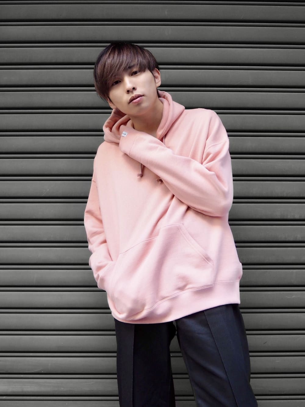 ピンク系のパーカー、ブラック系のデニムパンツを着用したメンズの秋コーディネートの1枚目の写真