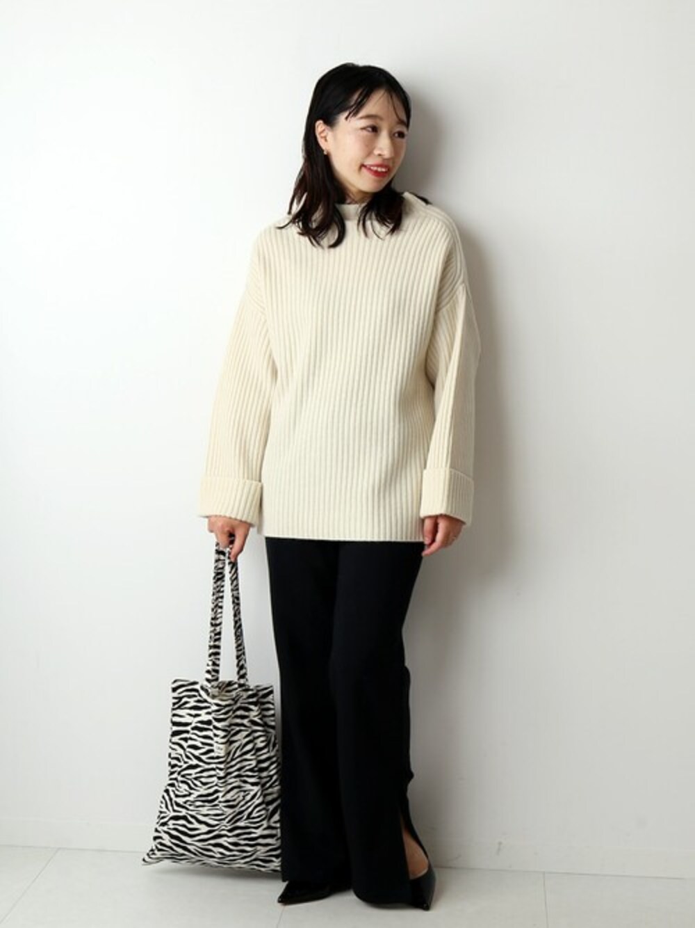 ホワイト系のニット/セーター、ブラック系のスウェットパンツを着用したレディースの秋コーディネートの1枚目の写真