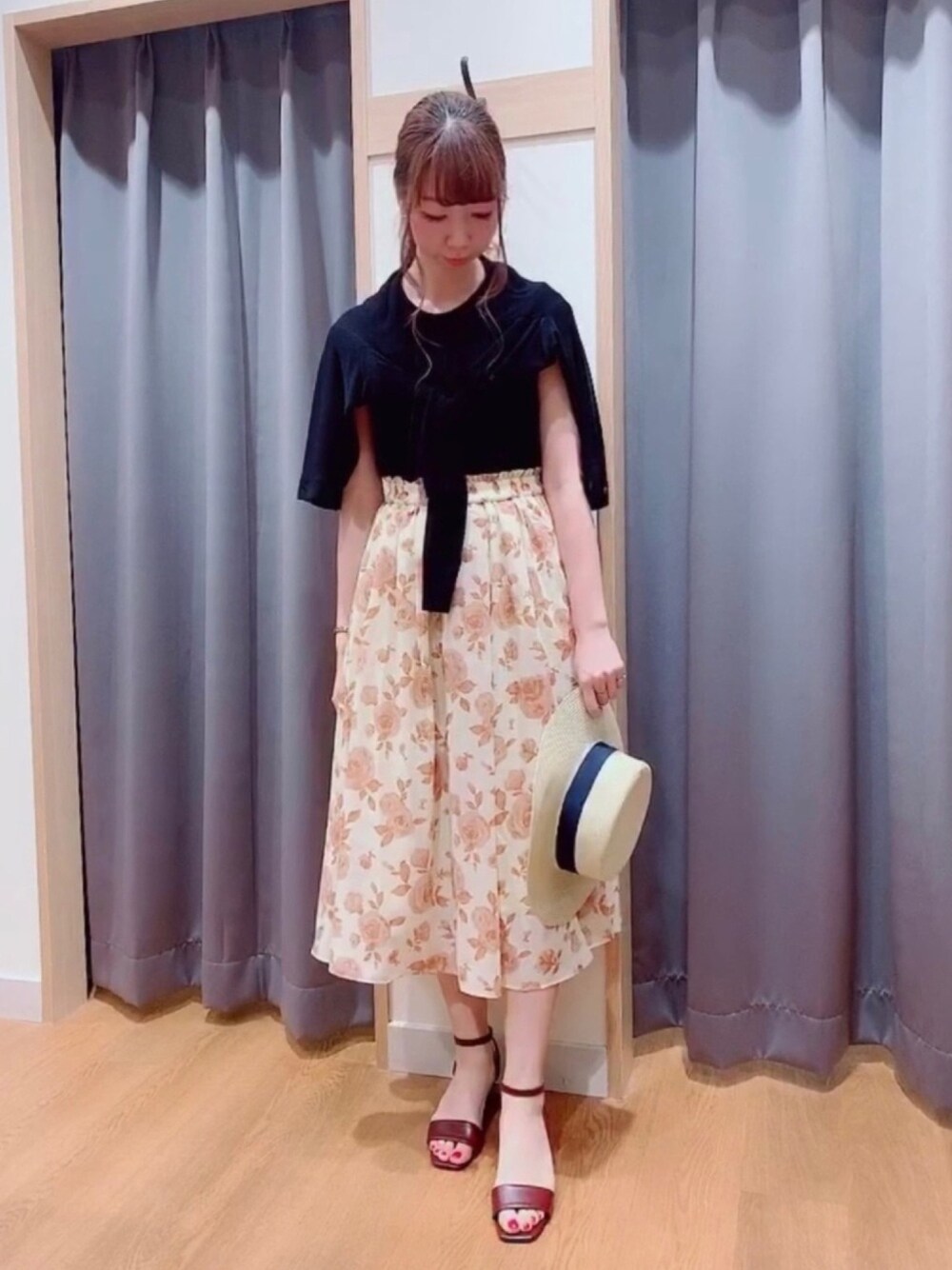 ベージュ系のスカート、レッド系のサンダル、ブラック系のニット/セーターを着用したレディースの夏コーディネートの1枚目の写真
