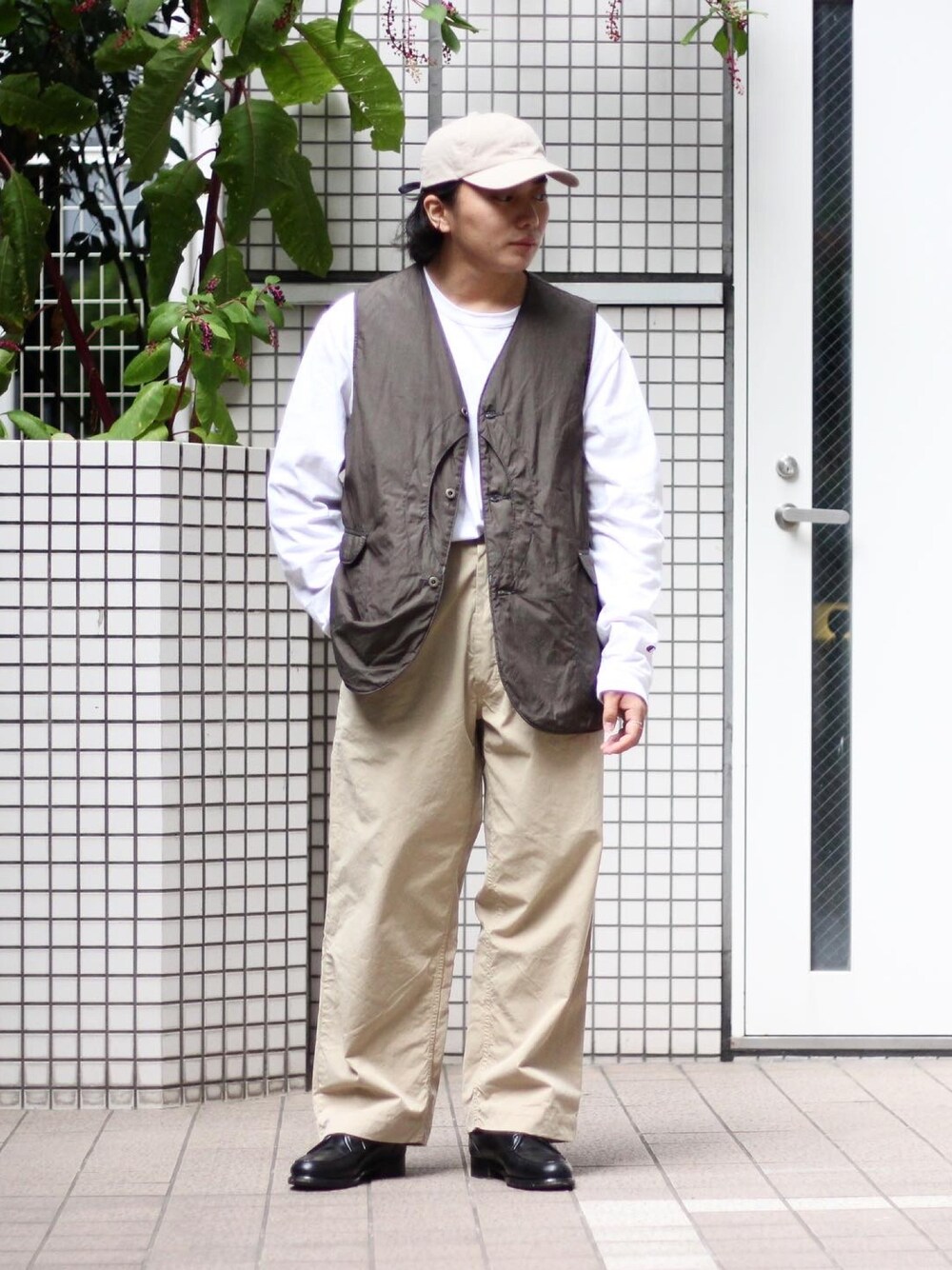 グリーン系のベスト、ホワイト系のTシャツ/カットソー、ベージュ系のチノパンツを着用したメンズの秋コーディネートの1枚目の写真