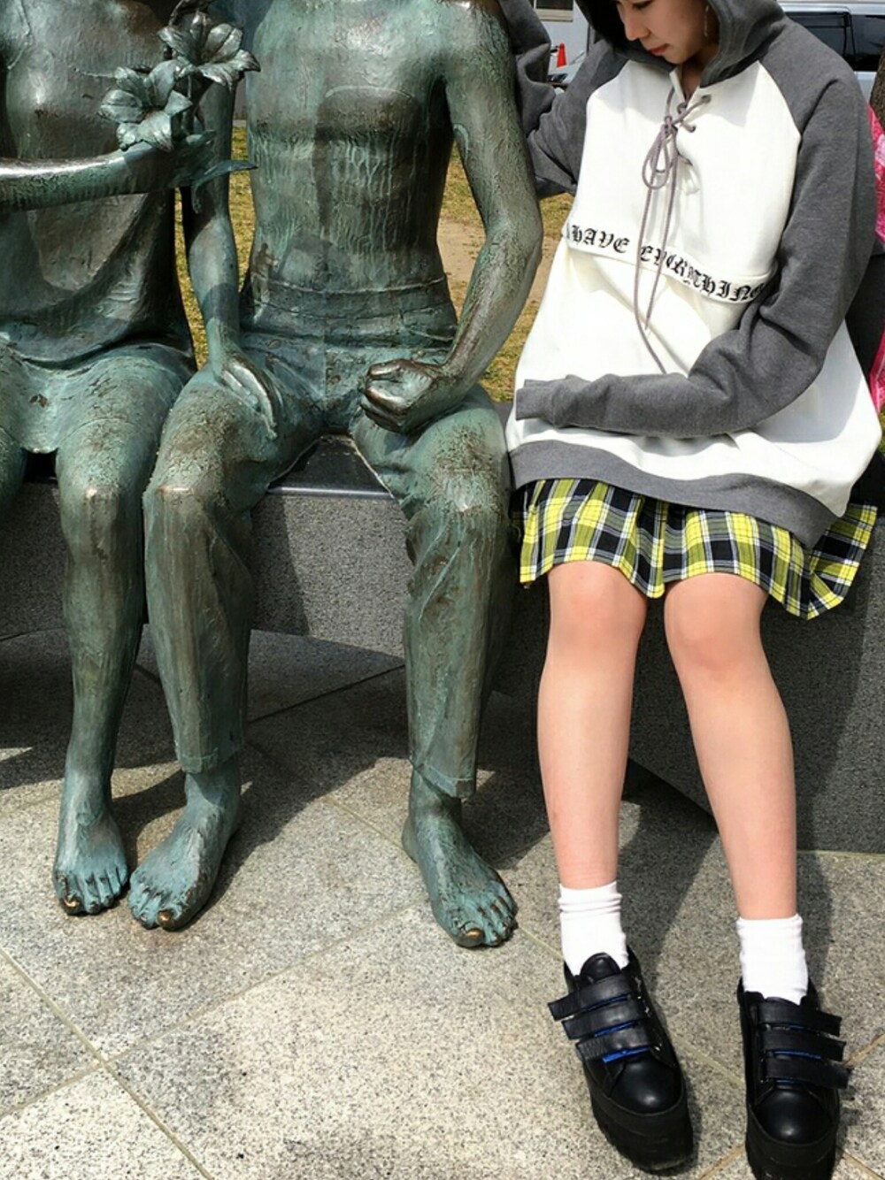 イエロー系のスカート、ブラック系のブーツ、グレー系のパーカーを着用したレディースの春コーディネートの1枚目の写真