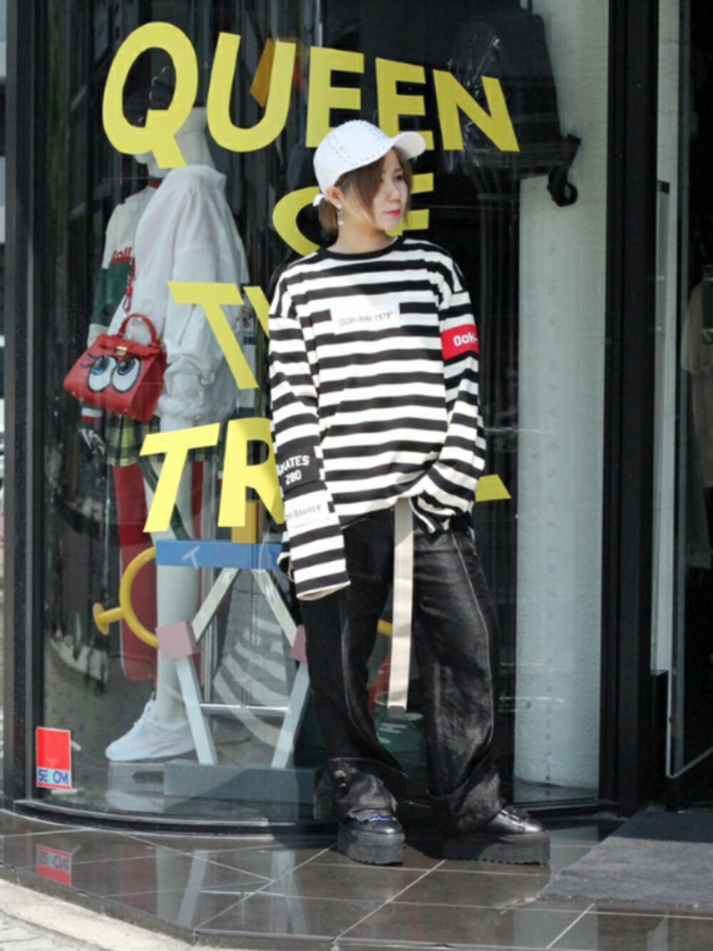 ブラック系のブーツ、ベージュ系のベルト、ホワイト系のキャップを着用したレディースの春コーディネートの1枚目の写真