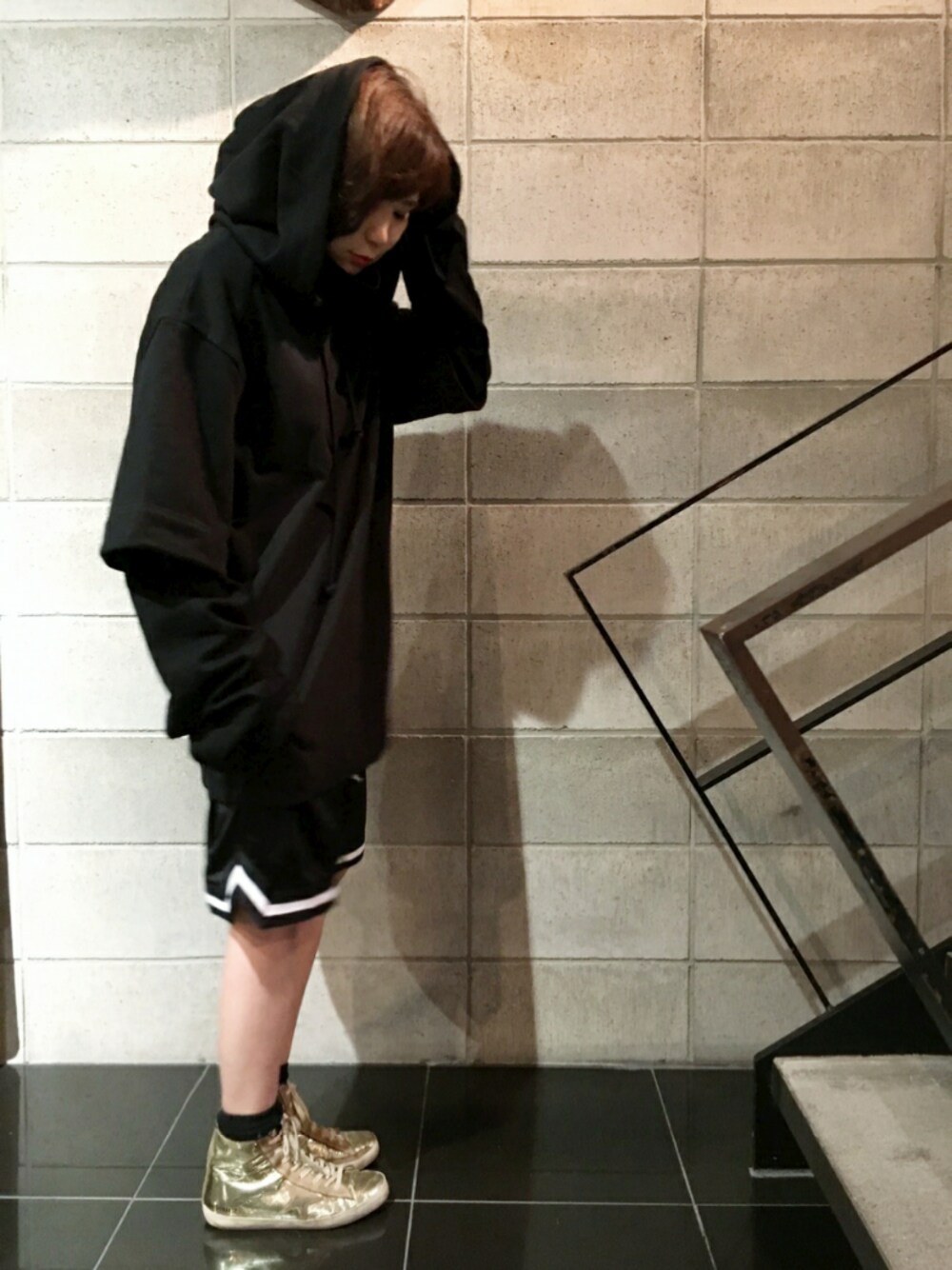 ブラック系のパーカー、ゴールド系のスニーカーを着用したレディースの夏コーディネートの1枚目の写真