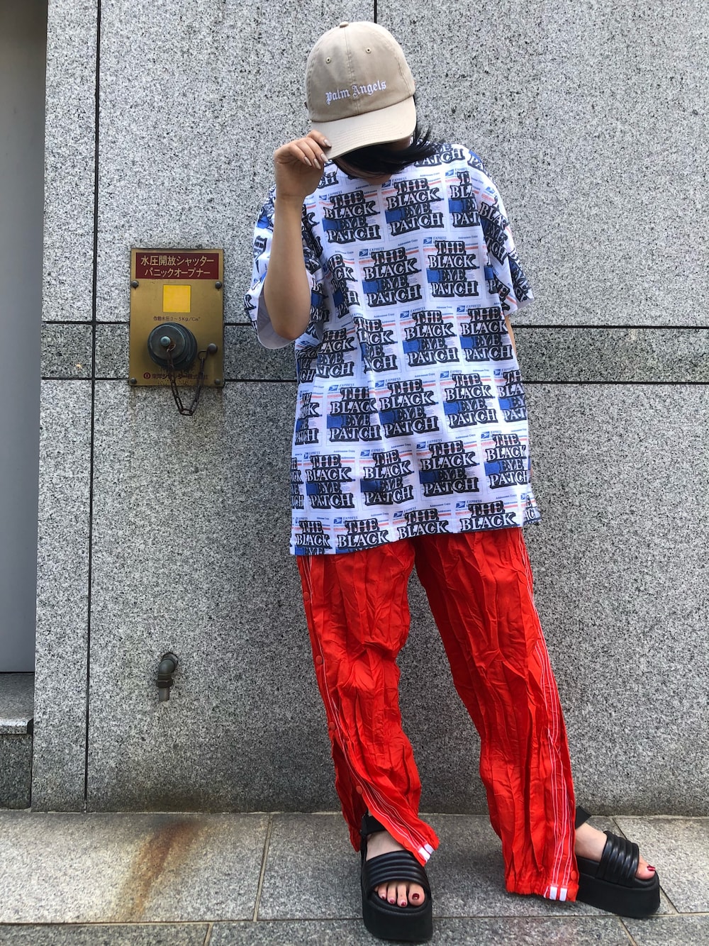 ブルー系のTシャツ/カットソー、レッド系のスラックス、ベージュ系のキャップを着用したレディースの夏コーディネートの1枚目の写真