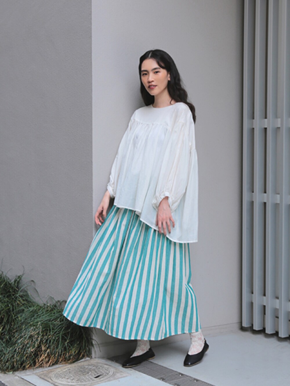 グリーン系のスカートを着用したレディースの春コーディネートの1枚目の写真