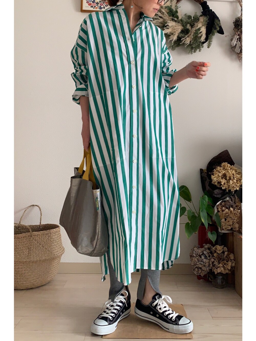 グリーン系のシャツワンピース、シルバー系のバッグ、ブラック系のスニーカーを着用したレディースの春コーディネートの1枚目の写真