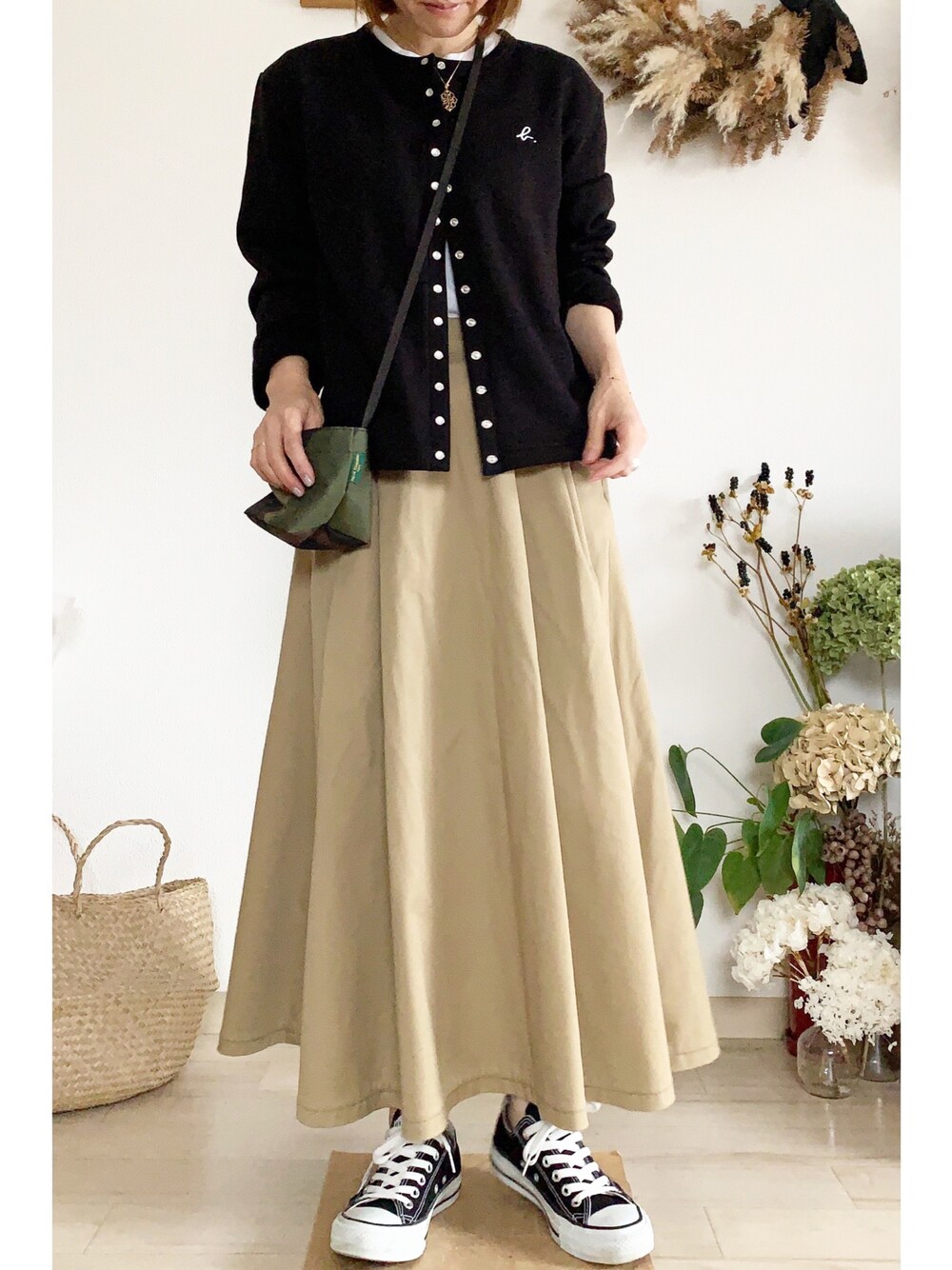 ブラック系のカーディガン/ボレロ、ベージュ系のスカート、ブラック系のスニーカーを着用したレディースの秋コーディネートの1枚目の写真