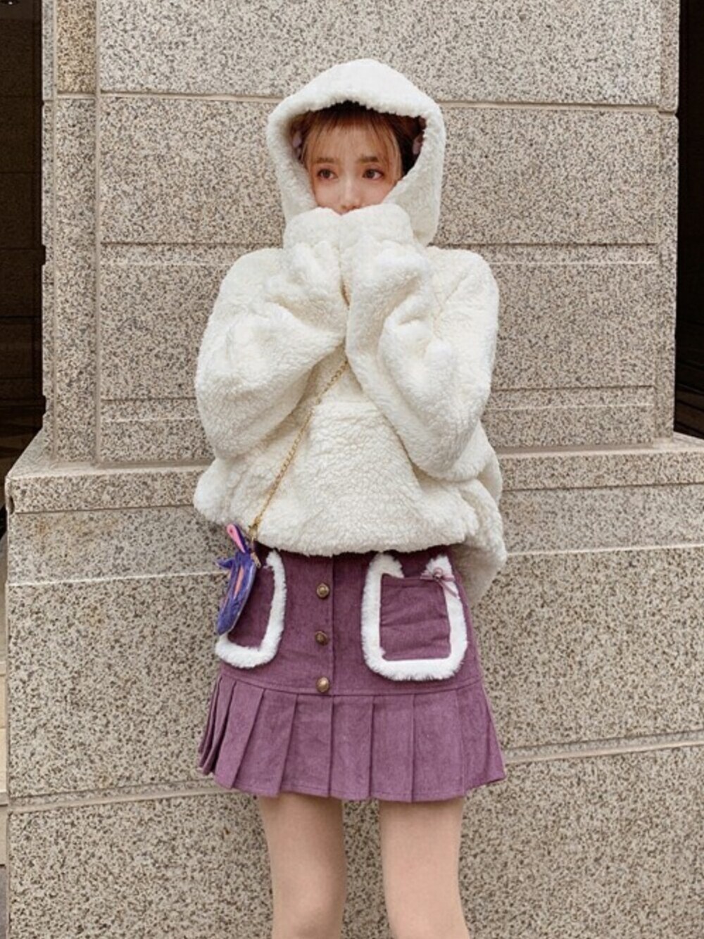 ホワイト系のパーカー、パープル系のスカートを着用したレディースの冬コーディネートの1枚目の写真