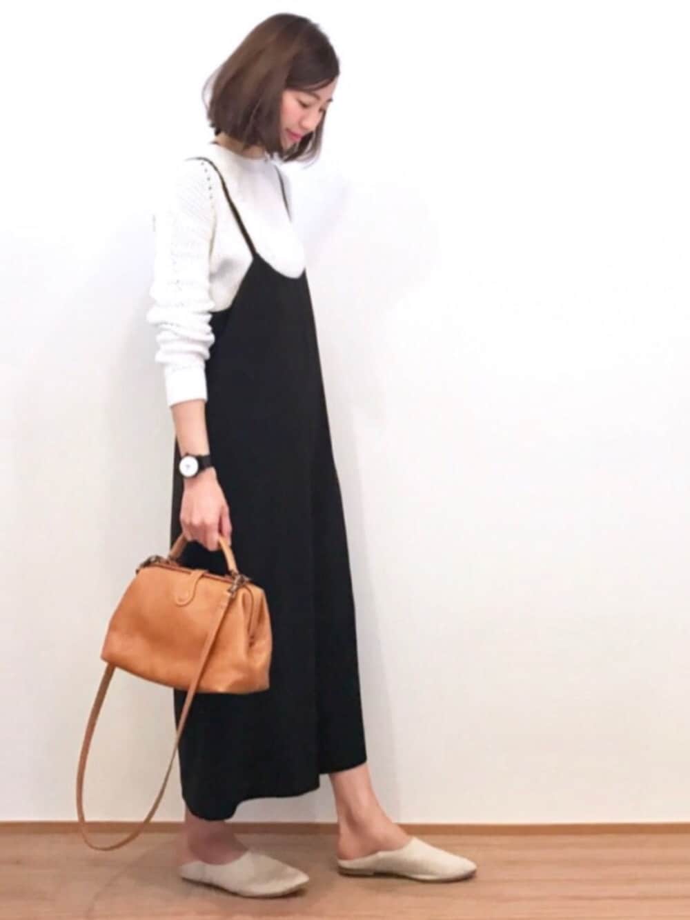 イエロー系のショルダーバッグ、ブラック系のサロペット/オーバーオール、ベージュ系のパンプスを着用したレディースの冬コーディネートの1枚目の写真